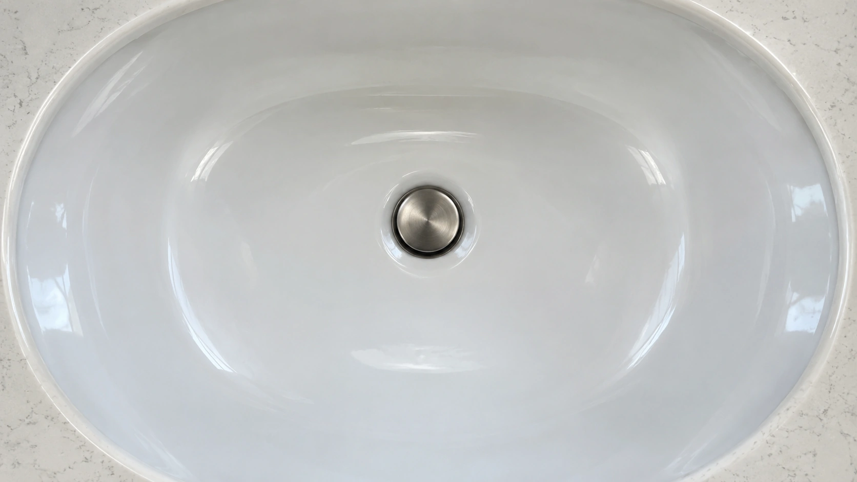 An empty bathroom basin and its drain.